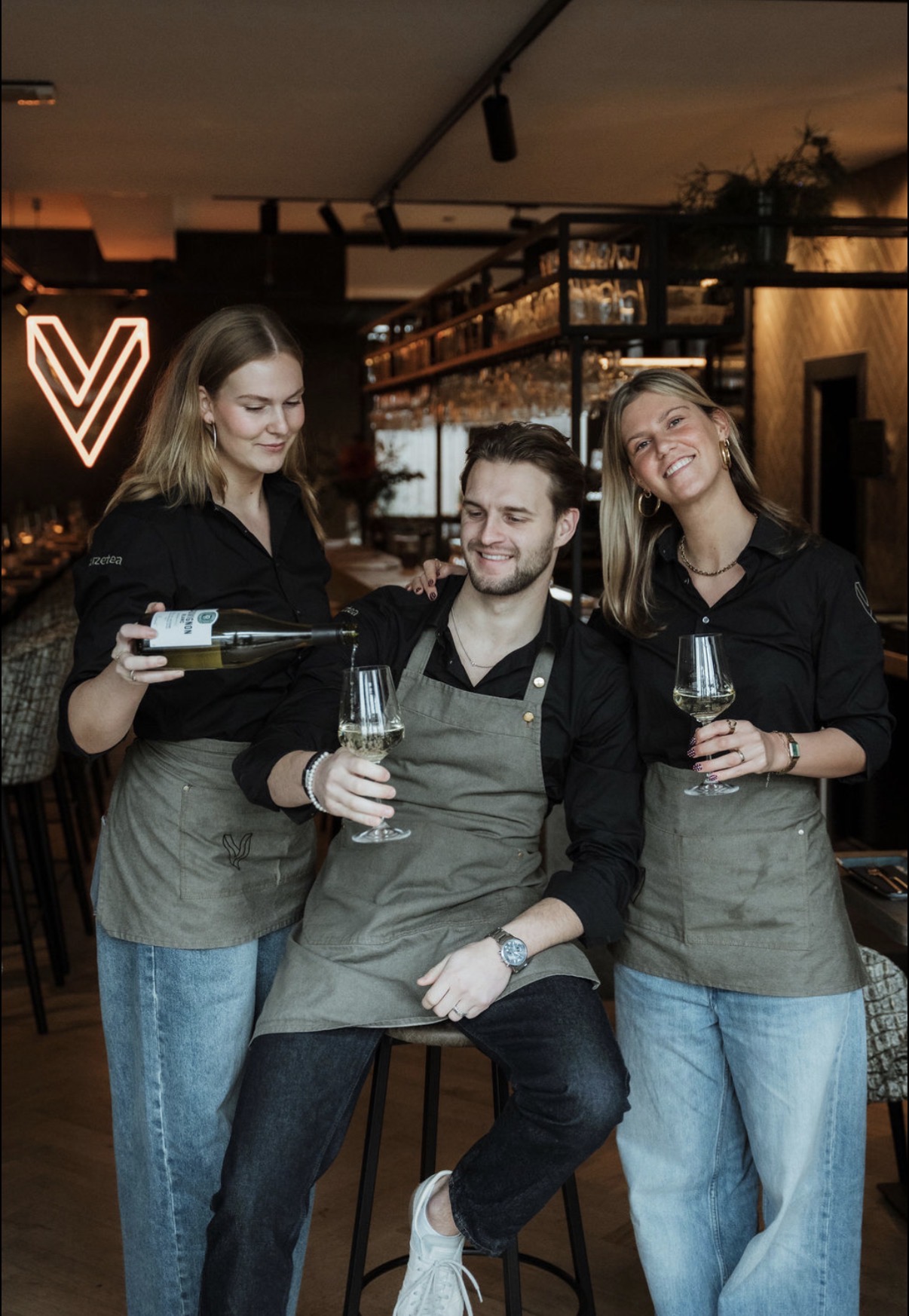 Bedieningsteam van Veemarktplein bij de bar met neon V